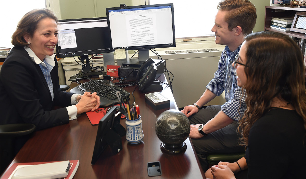 Dr. Aguirre talks to two students